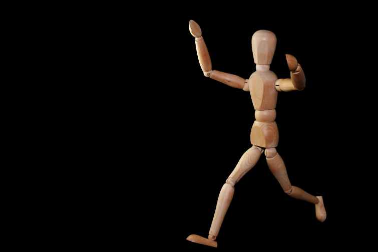 timelapse photography of brown wooden puppet running on a black screen