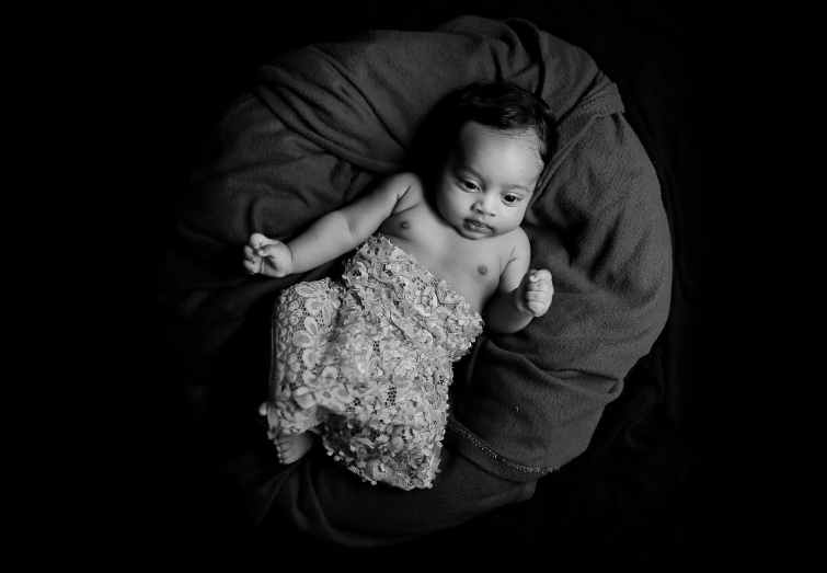 grayscale photo of baby lying on blanket