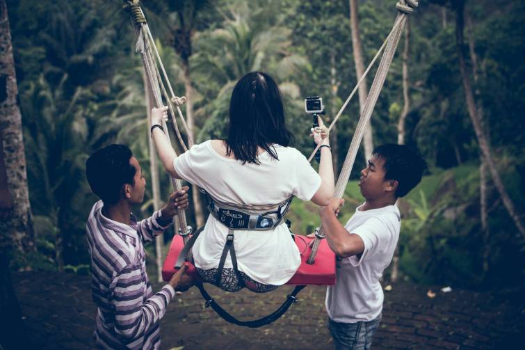 two men assisting woman riding on swing